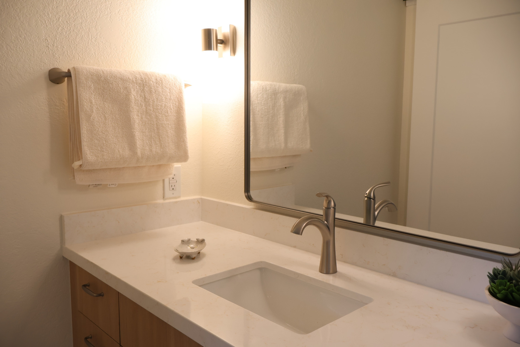 Kailua bathroom vanity with light wood-tone cabinetry, natural quartz countertop, and brushed nickel fixtures in a coastal sea-and-sand palette.